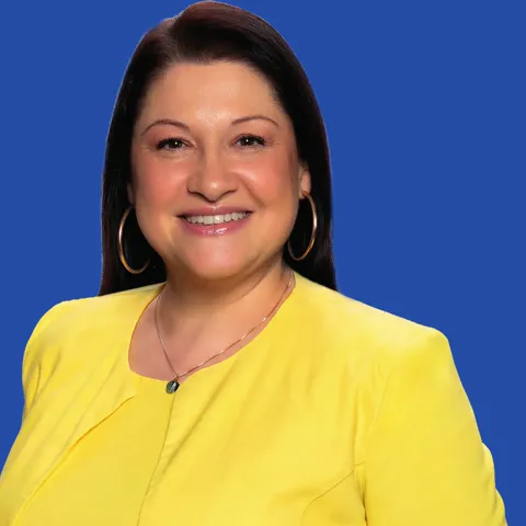 Ada Munaretto, de blazer amarelo, sorrindo.
